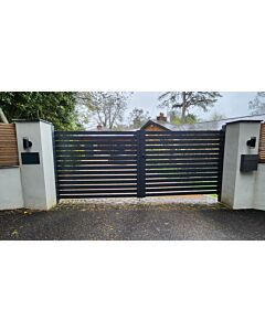 Anthracite grey liberty metal driveway gate outside house with stone fence either side